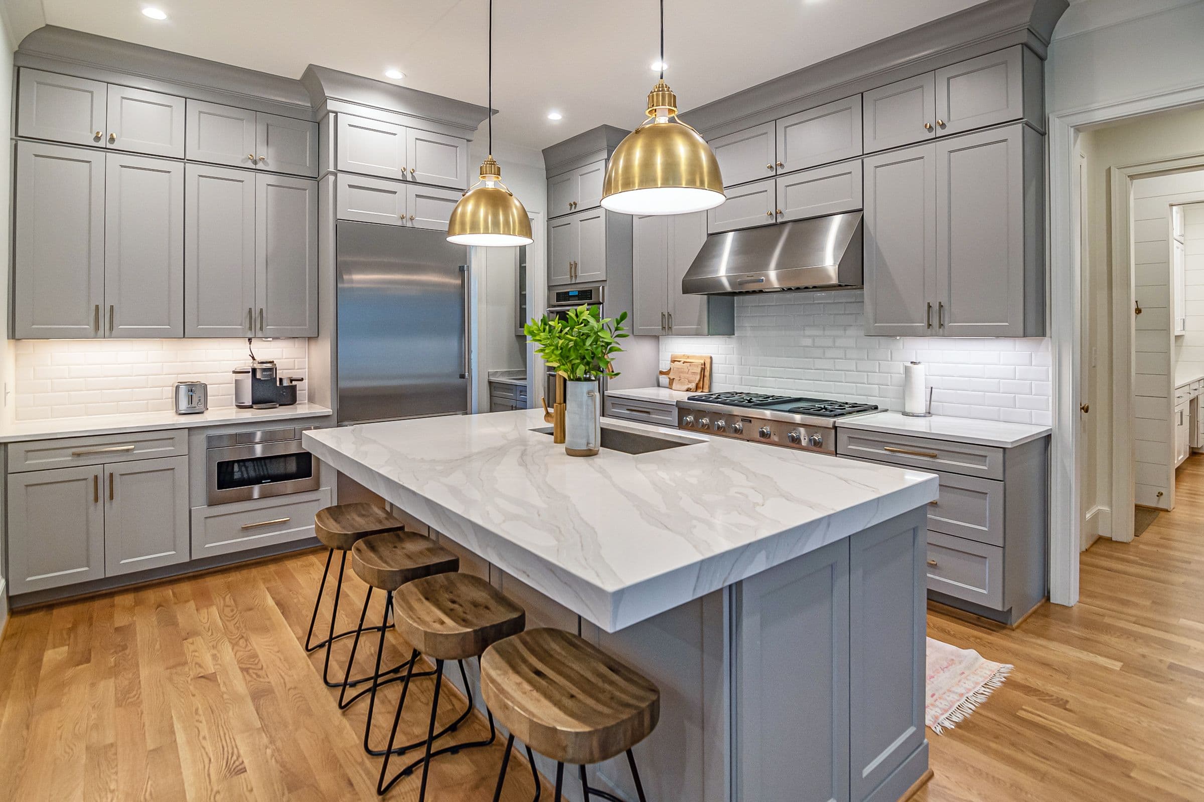 Kitchen Remodeling with Gray Cabinets and a Large Island Kitchen remodeling near you: gray shaker cabinets, a large white island, brass pendant lights and wood flooring